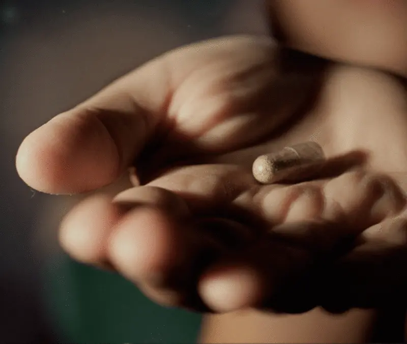 Close-up of hand holding a single small pill