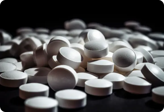 A pile of white pills on a black background.