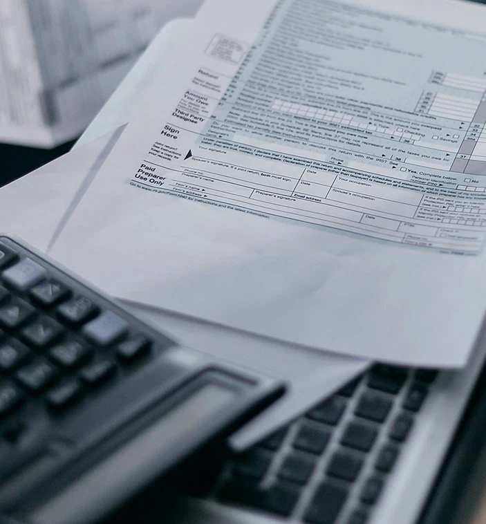 Irs forms and a calculator on top of a laptop.